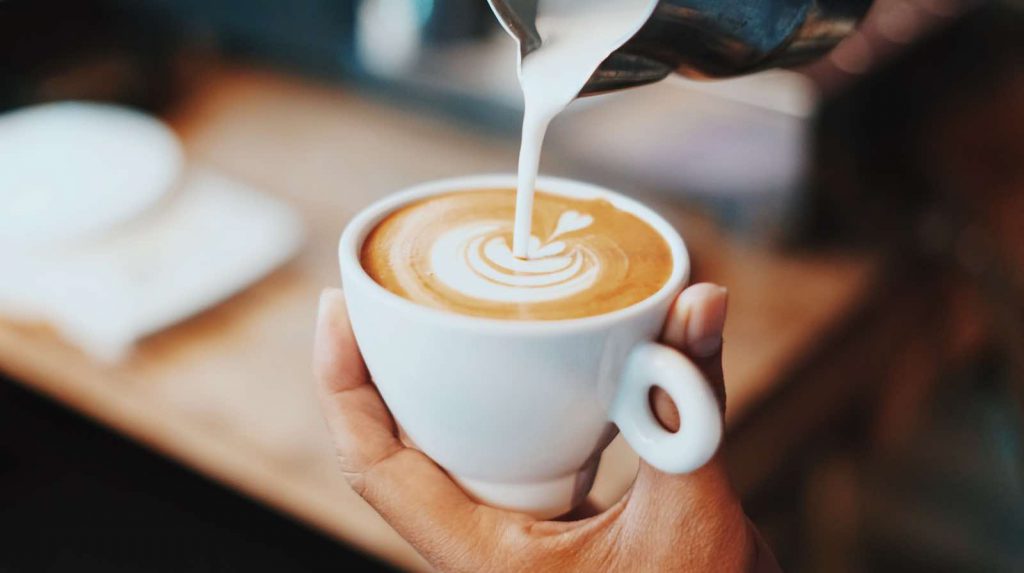 Tasse Cappuccino wird eingeschenkt