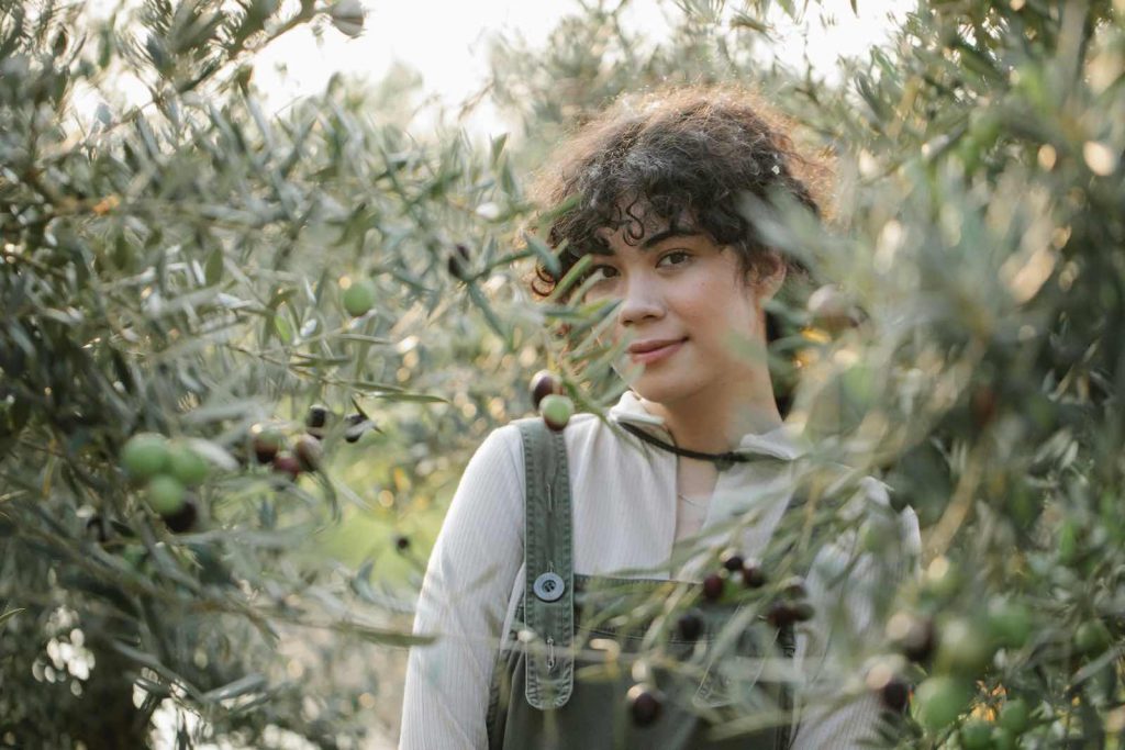 Mädchen steht zwischen Olivenbäumen